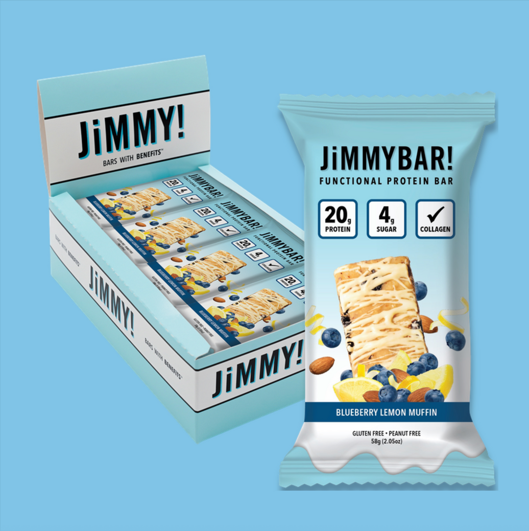 A retail display box and a single wrapped JiMMYBAR! protein bar on a solid light blue background. The packaging is light blue and white with dark blue text and graphics, featuring a blueberry lemon muffin illustration.