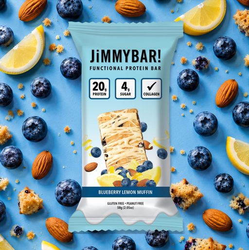 A JimmyBar functional protein bar in Blueberry Lemon Muffin flavor, presented in a light blue wrapper surrounded by blueberries, almonds, lemon slices, and cookie crumbs on a bright blue background.